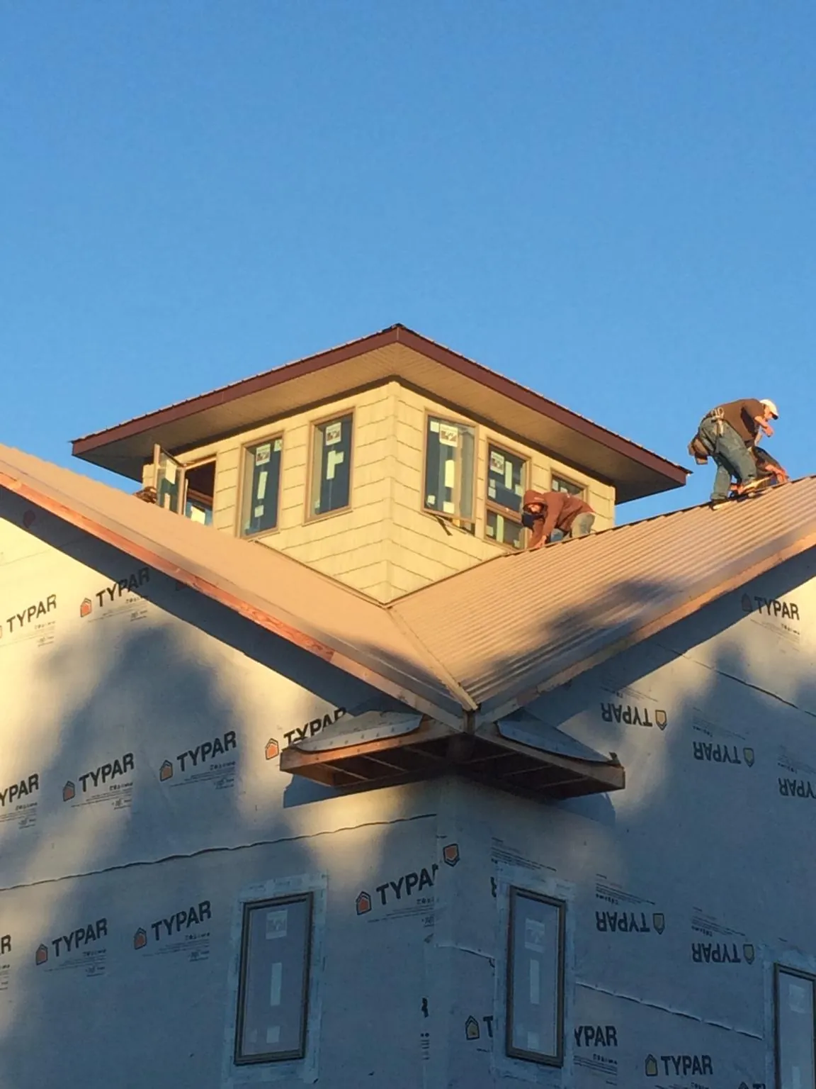 Roofers working around a rooftop cupola on a new metal roof at sunset — Roof Waterproofing in Metamora by Roofing Brothers